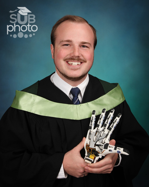 Engineering grad holding a mechanical hand
